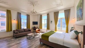 Une chambre d’hôtel avec un grand lit, un canapé, une petite table et un téléviseur.