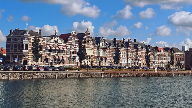 Un bâtiment situé au bord de l’eau, doté d’une rangée de fenêtres uniformes et d’une façade en pierre.