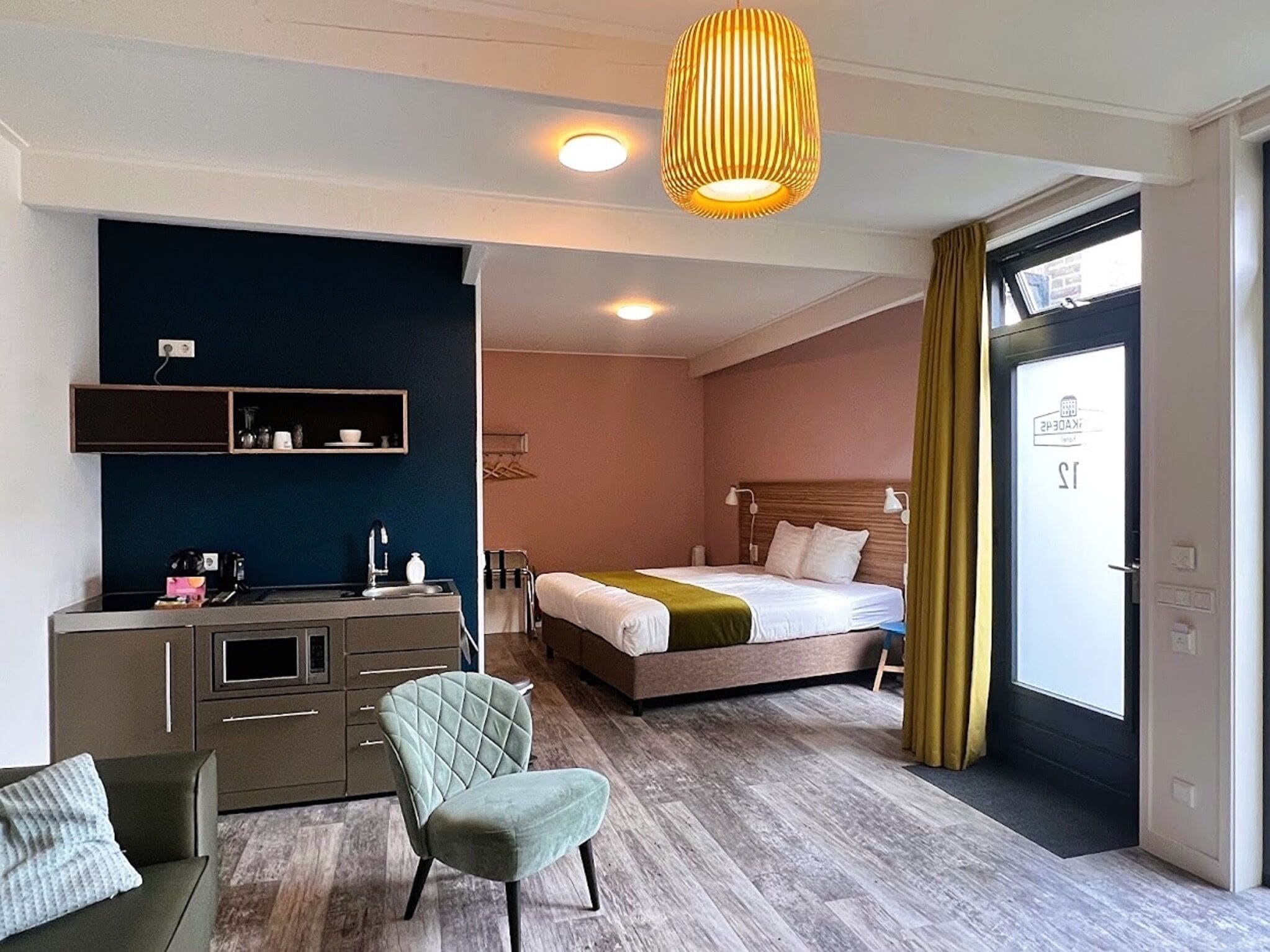 A hotel room with a bed, a desk, a chair, a wardrobe, and a window with curtains.