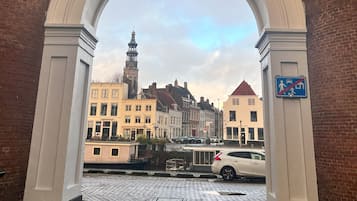An archway leading to a cobblestone street with historic buildings and a church tower.