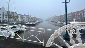 Un canal bordé de bateaux amarrés, un pont blanc et des bâtiments qui longent la rive.