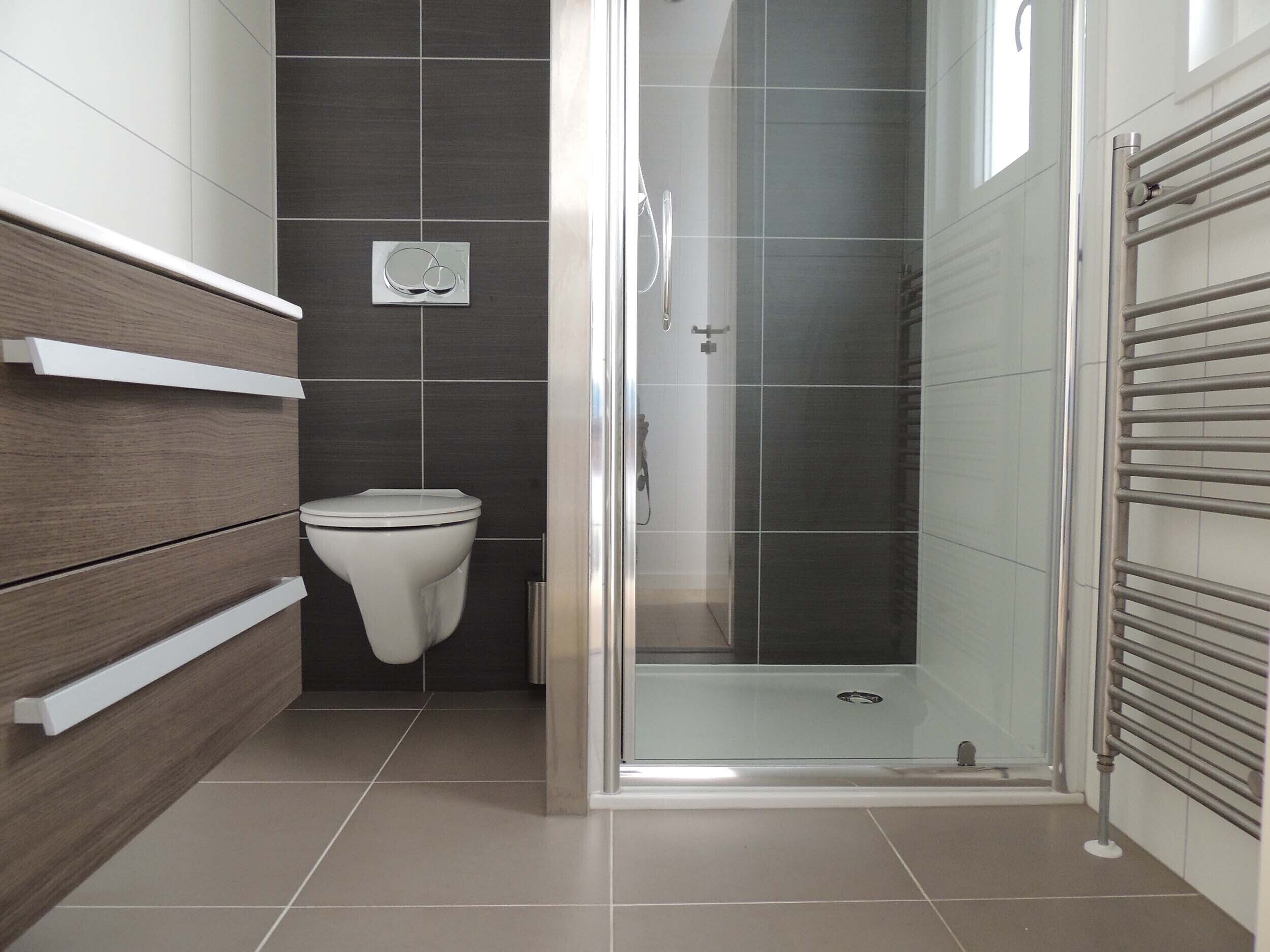 A modern bathroom with a toilet, a shower, and a glass-enclosed shower stall.