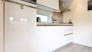 Une cuisine moderne avec des meubles blancs, une fenêtre et une hotte de cuisinière en acier inoxydable.