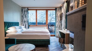 A hotel room with a large bed, a desk, and a view of the outdoors. - Alpenrose Aktiv & Spa (Schruns)