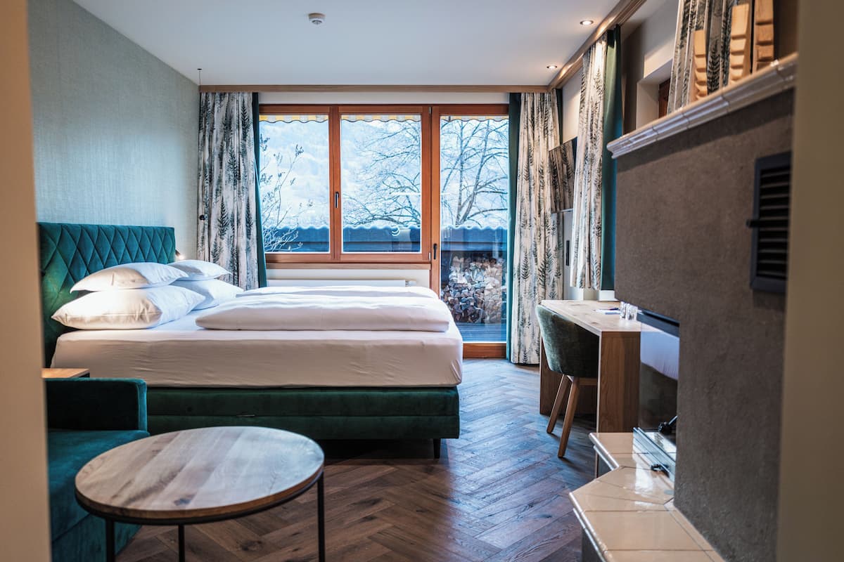A hotel room with a large bed, a desk, and a view of the outdoors.