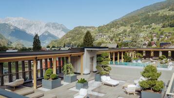A rooftop terrace with a pool, lounge chairs, and potted plants.