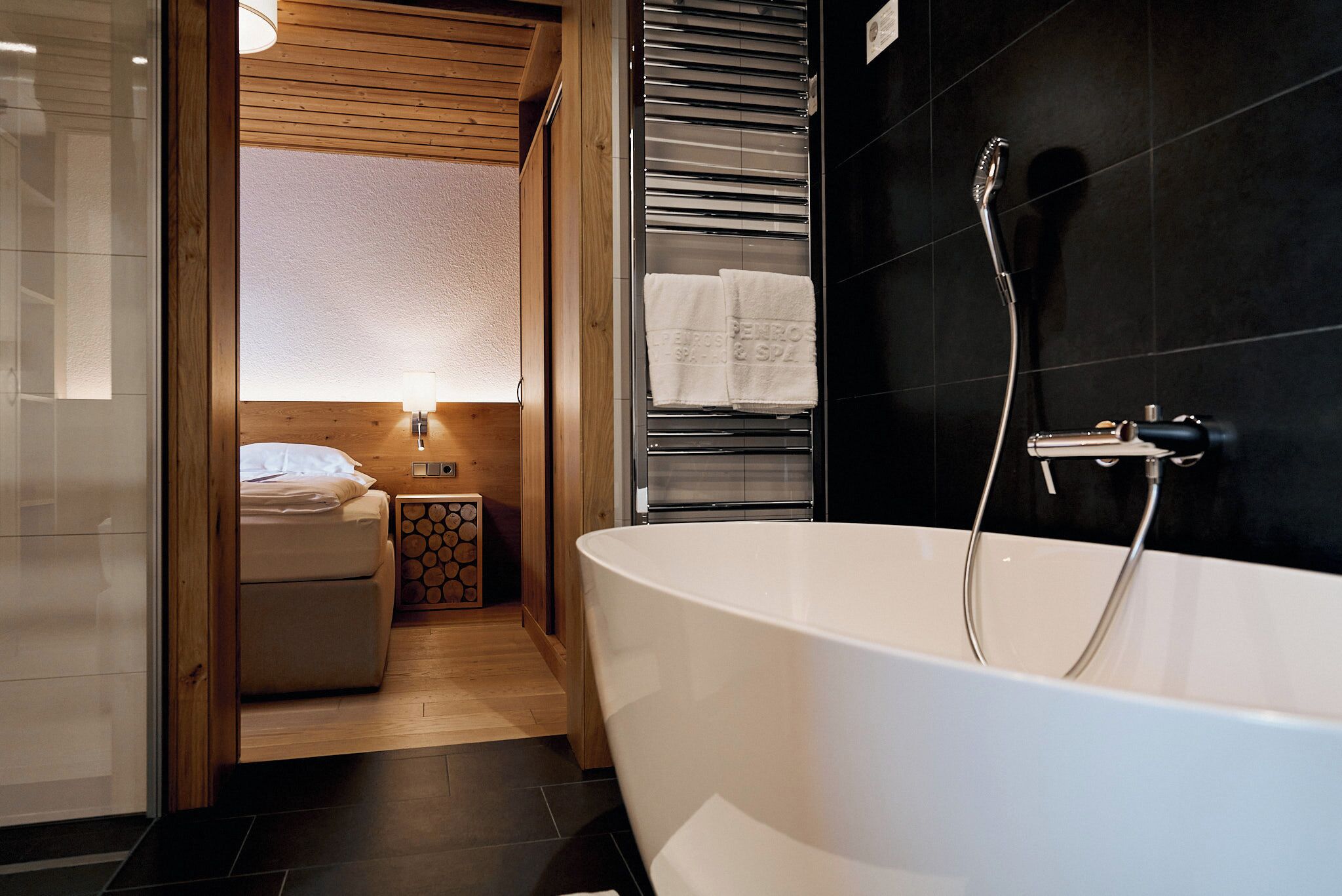 Une salle de bain moderne avec une baignoire sur pieds, un porte-serviettes avec des serviettes et une petite table de chevet avec une lampe.