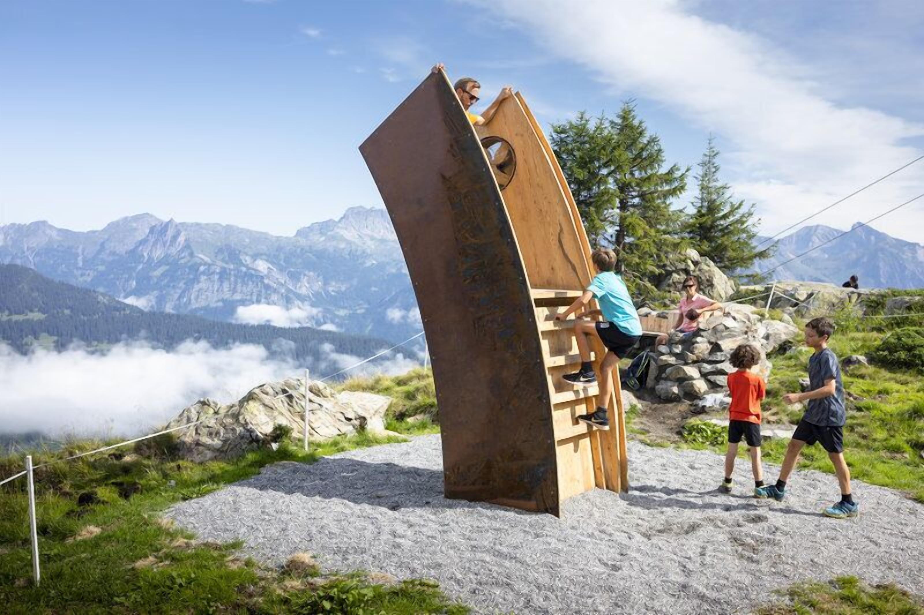 A wooden structure with a curved design, set against a mountainous backdrop.