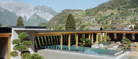 A rooftop pool area with a view of a mountainous landscape.