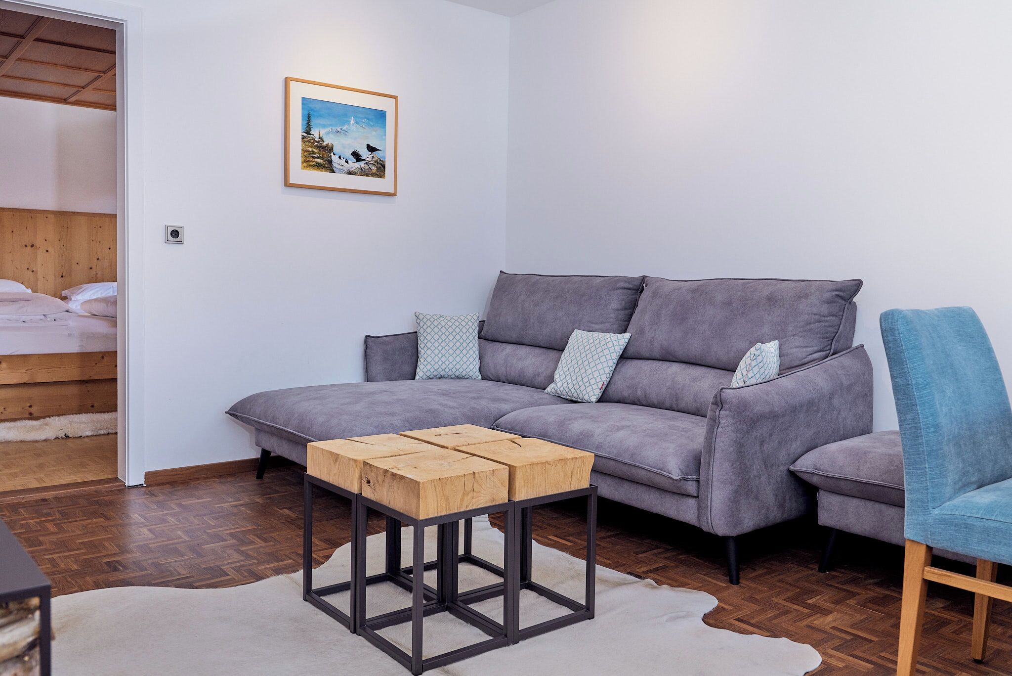 Una sala de estar moderna con un sofá gris, una mesa de centro de madera y una silla azul.