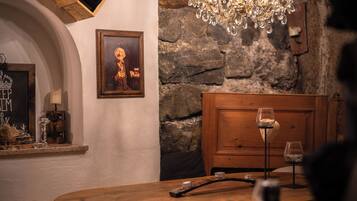 A rustic dining area with a wooden table, a chandelier, and a wine rack with bottles.
