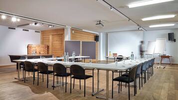 Ein Konferenzraum mit langem Tisch, Stühlen, einer Tafel und einem Projektor.