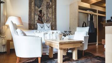 Una sala moderna con un sofá, dos sillones, una mesa de centro de madera y un tapiz grande en la pared.