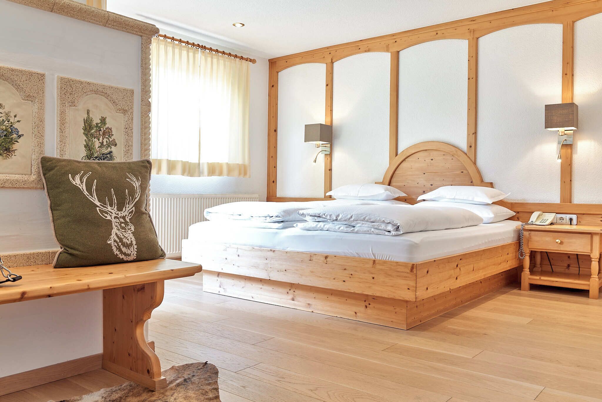 Ein Schlafzimmer mit Holzrahmen, einem Bett, Nachttischen und einer Bank.