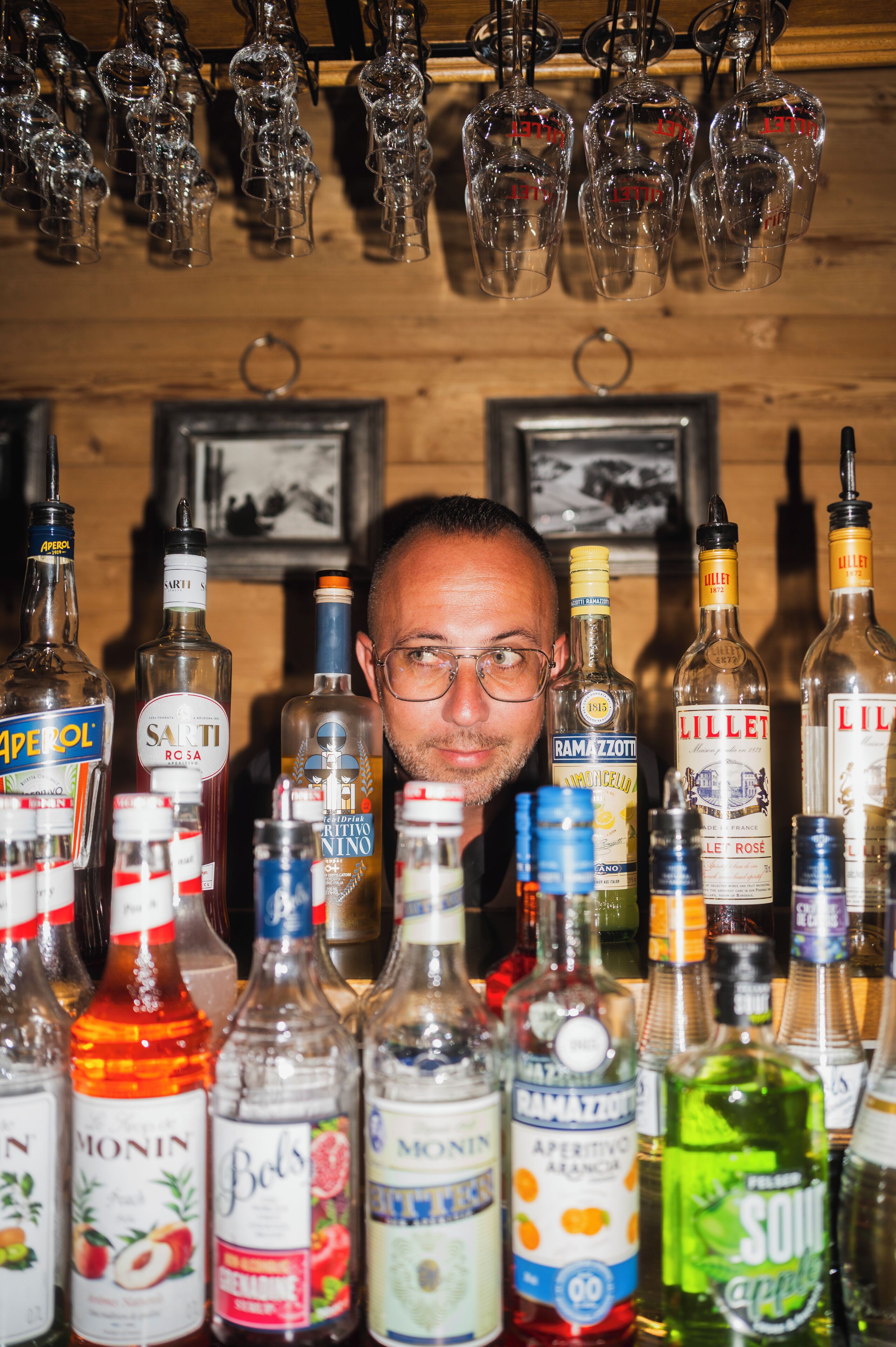 A bar area with various liquor bottles and hanging wine glasses.