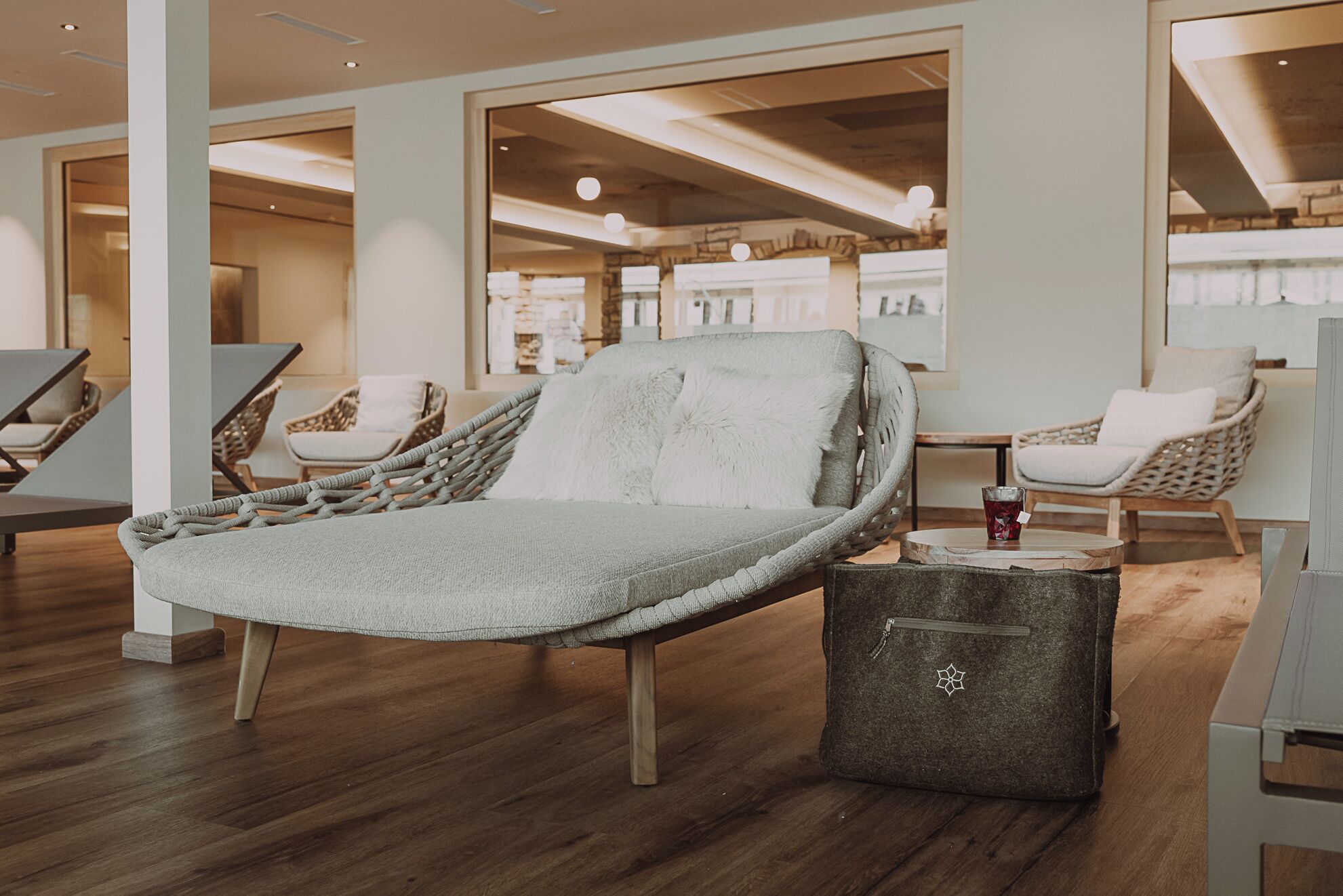 Un espace de détente moderne, avec un fauteuil confortable, des chaises en osier et une petite table sur laquelle est posée une boisson.