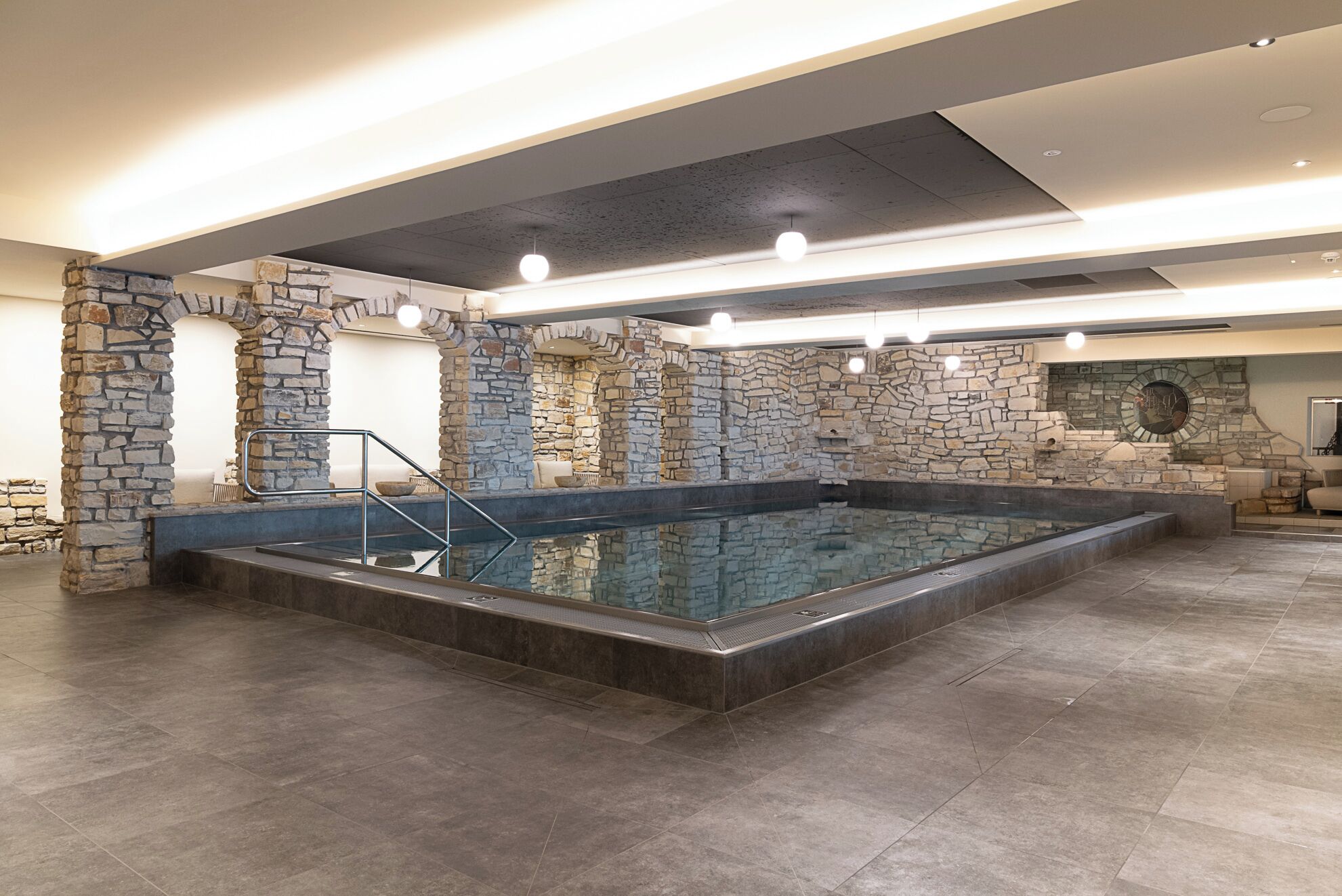 Ein geräumiger, überdachter Pool mit Steinwänden und modernem Design.