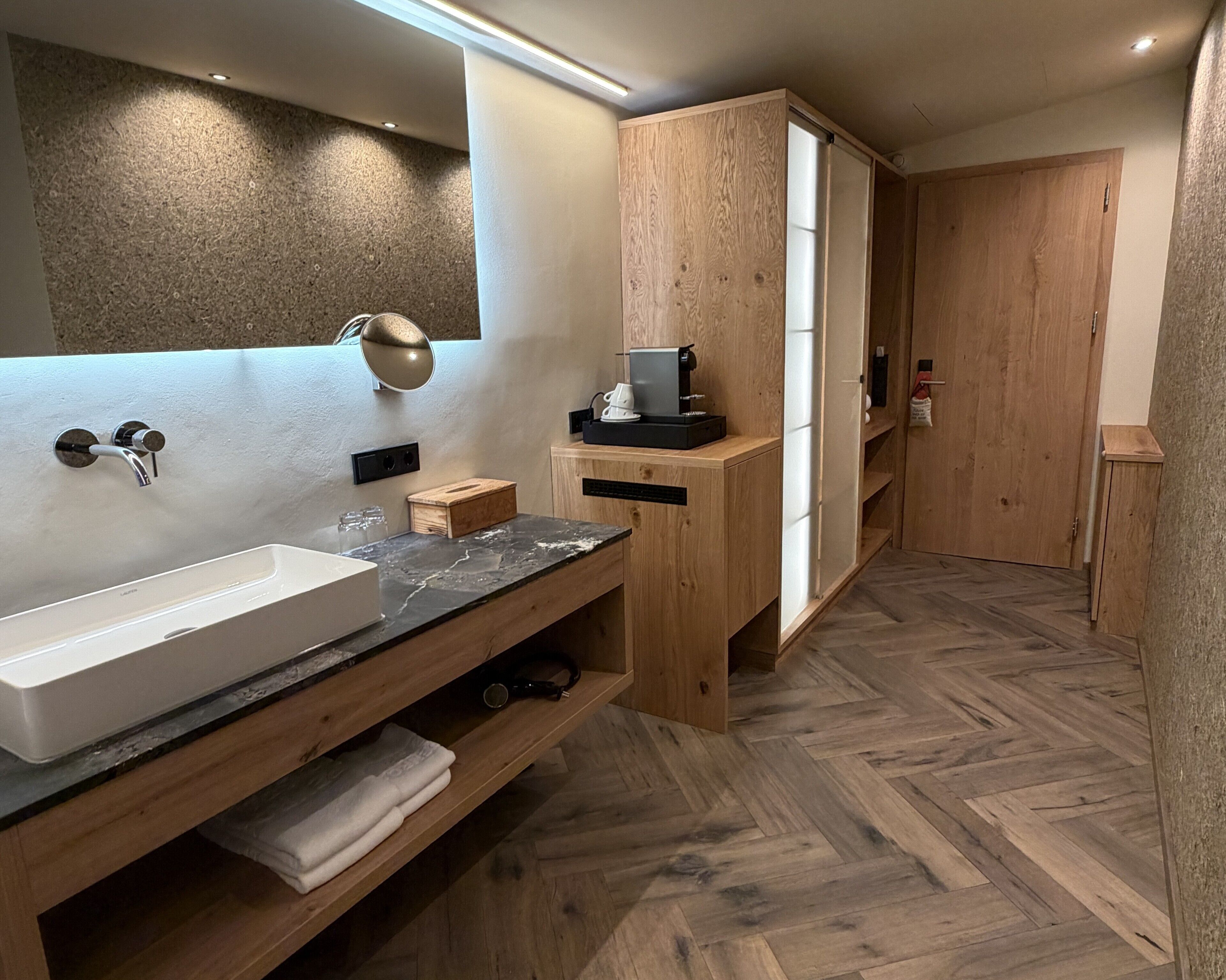 Un baño moderno con un espejo grande, un lavabo blanco y un mueble de tocador de madera.