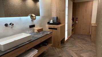 Un baño moderno con un espejo grande, un lavabo blanco y un mueble de tocador de madera.