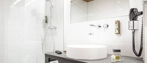 Un baño moderno con un lavamanos redondo, un espejo, un secador de pelo y un perchero para toallas.