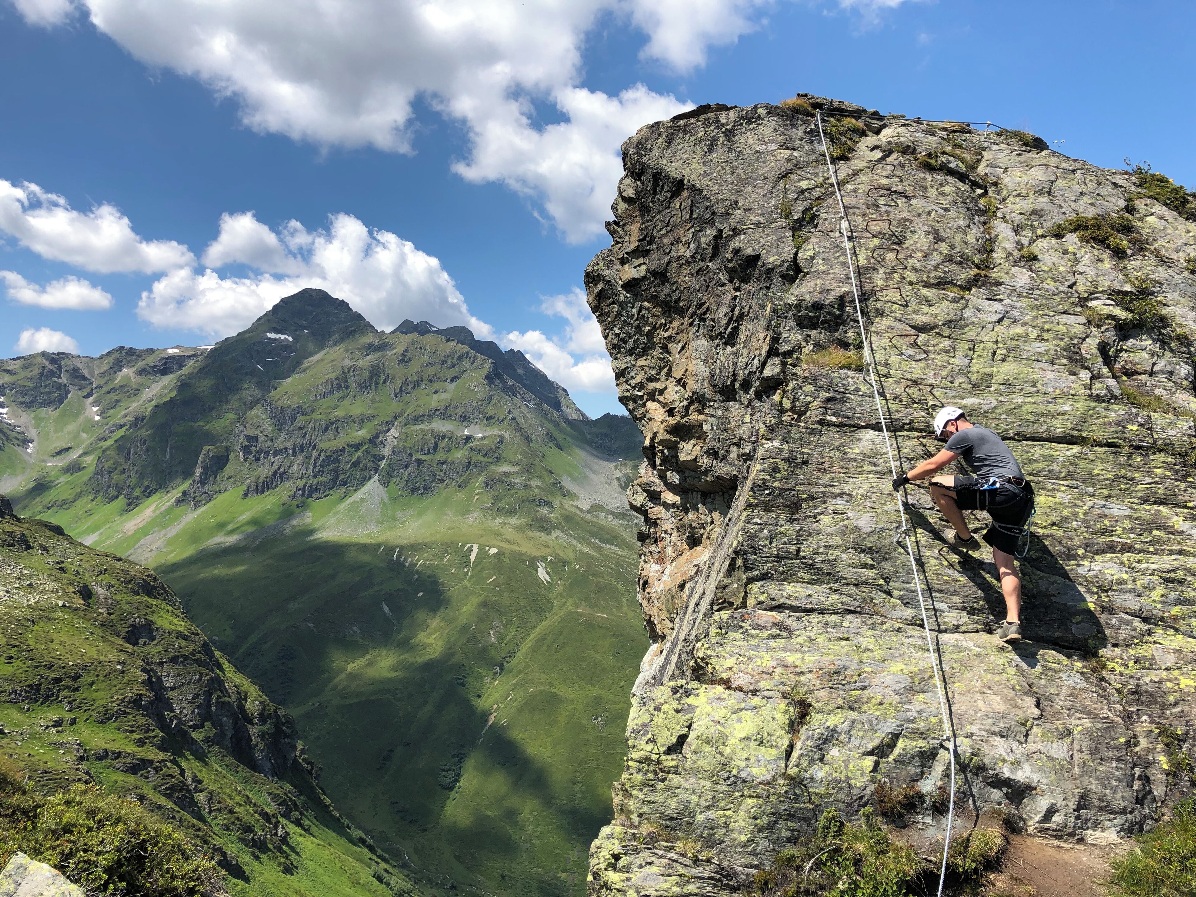Una persona escalando una gran formación rocosa con un paisaje montañoso al fondo.