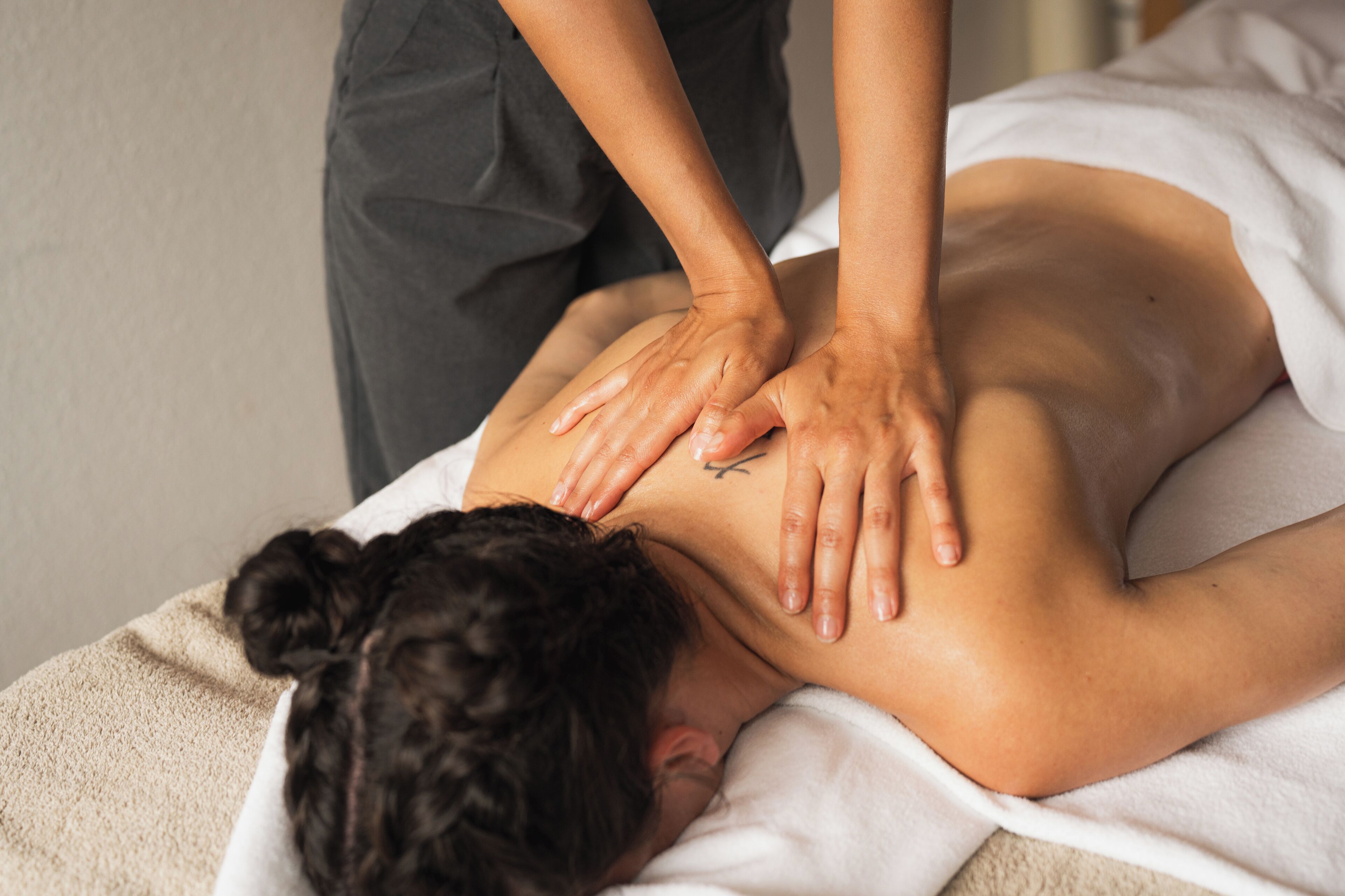 A person receiving a back massage on a bed.