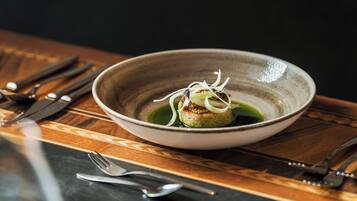 A bowl of food on a table with cutlery around it.