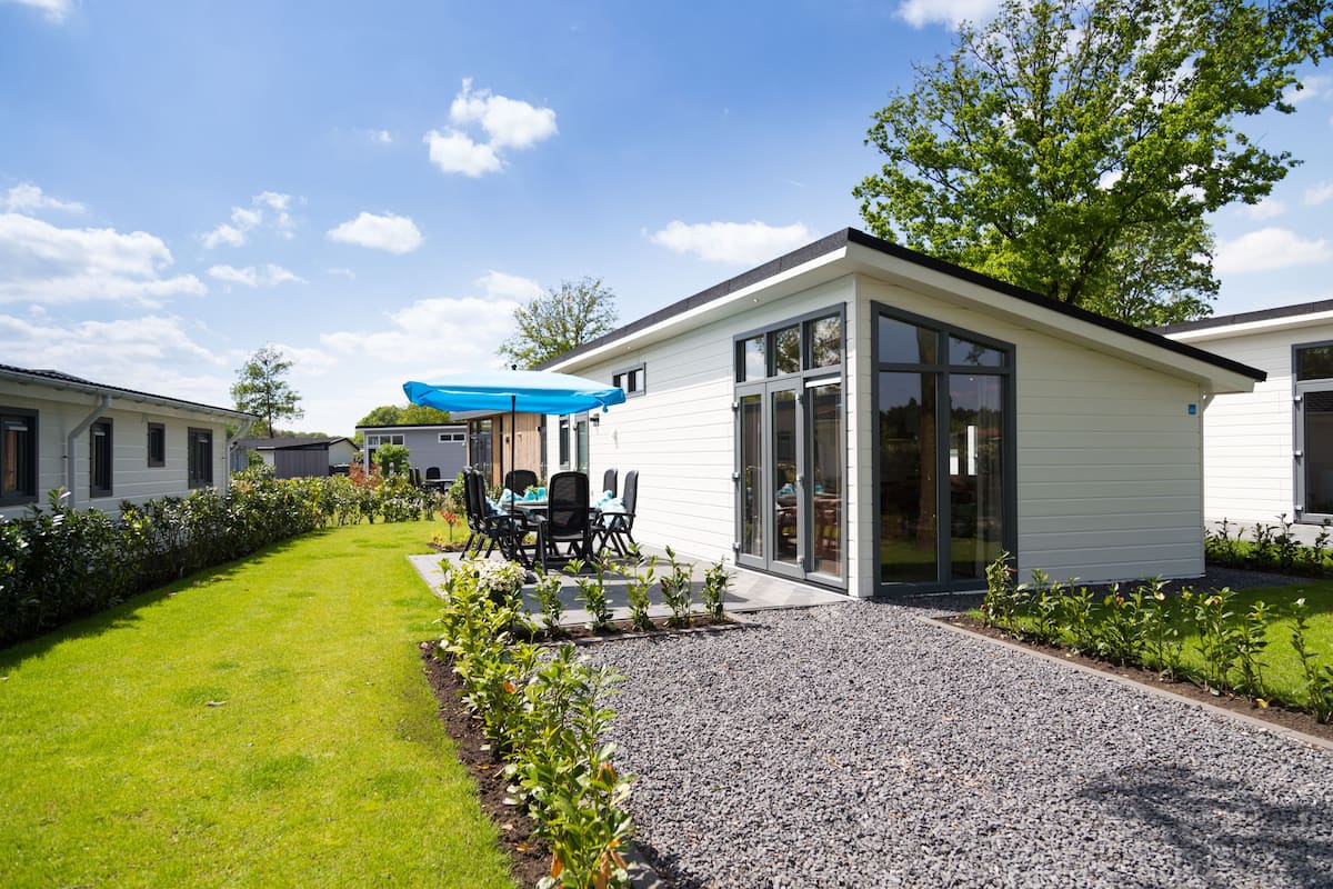 A modern building with a gravel driveway, a patio with outdoor furniture, and a well-maintained lawn.