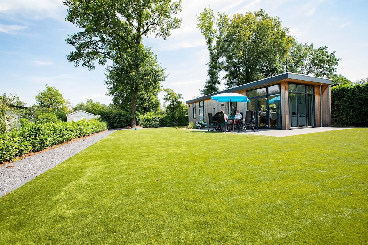A modern house with a glass conservatory, a well-maintained lawn, and a gravel path.