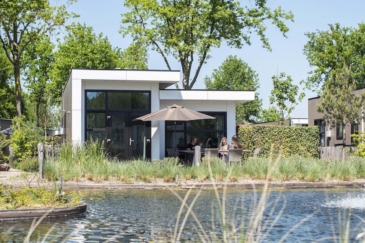 A modern house with a patio area and a pond.