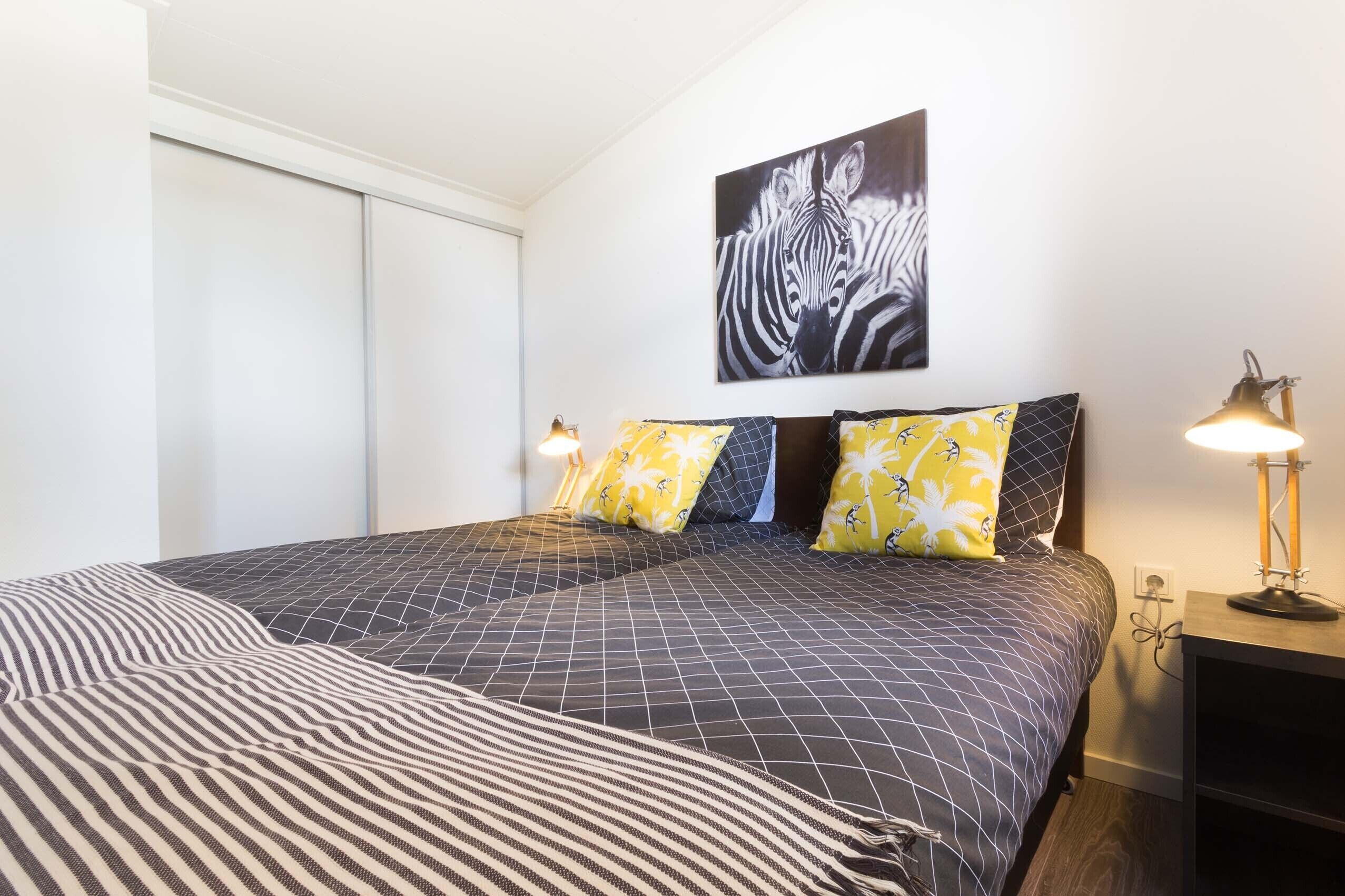 A bedroom with a bed, a zebra painting, and a lamp.