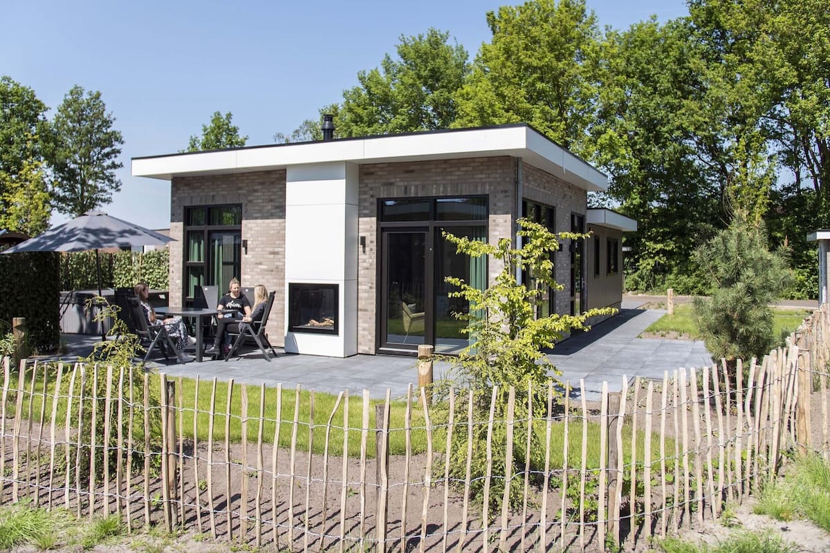 A modern house with a patio area, a fireplace, and a fenced garden.