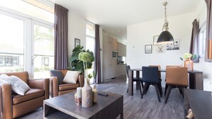 Una sala de estar moderna con sofás de cuero, una mesa de centro de madera y un comedor con sillas y una mesa.