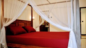 A bed with a red mattress and white canopy. - Wayside Guest (Mirissa)