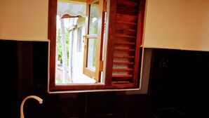 A bathroom with a window, a sink, and a wooden door. - Wayside Guest (Mirissa)