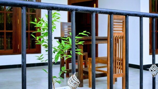 A balcony with a metal railing, wooden chairs, and a table. - Wayside Guest (Mirissa)