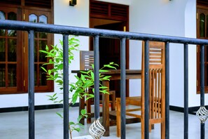 A balcony with a metal railing, wooden chairs, and a table. - Wayside Guest (Mirissa)