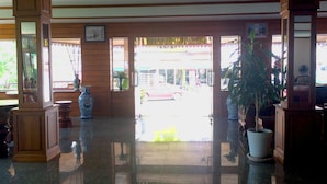 A lobby with wooden paneling, a large potted plant, and a view of the street outside.