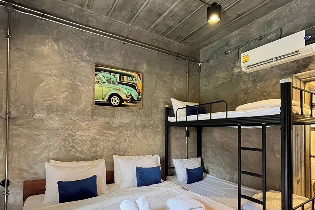 A bunk bed room with a single bed, two pillows, a wooden headboard, and a wall-mounted air conditioner.