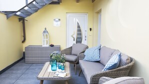Un rincón al aire libre acogedor con muebles de mimbre, una mesita con bebidas y un farol.