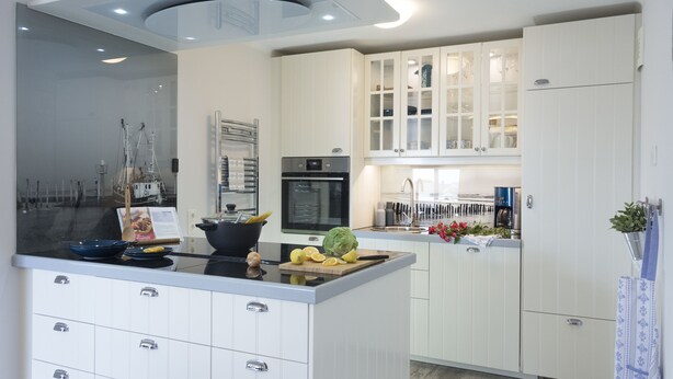Una cocina moderna con armarios blancos, una isla central con encimera negra y un horno empotrado.