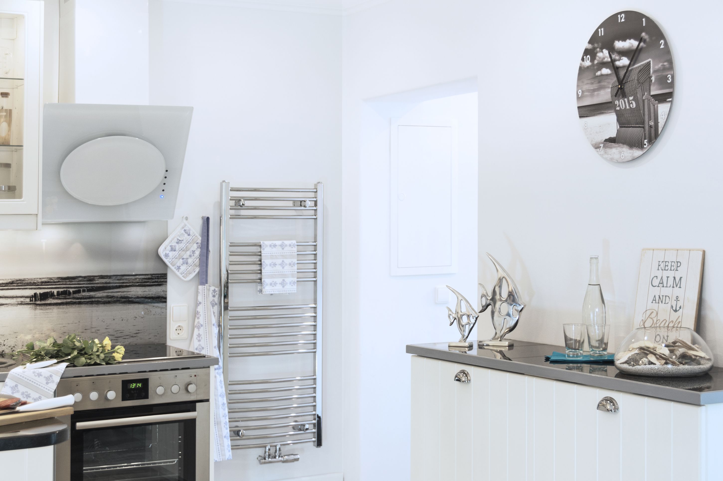 A modern kitchen with stainless steel appliances, a glass door refrigerator, and a decorative clock on the wall.