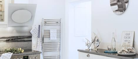 Una cocina moderna con electrodomésticos de acero inoxidable, un refrigerador con puerta de vidrio y un reloj decorativo en la pared.