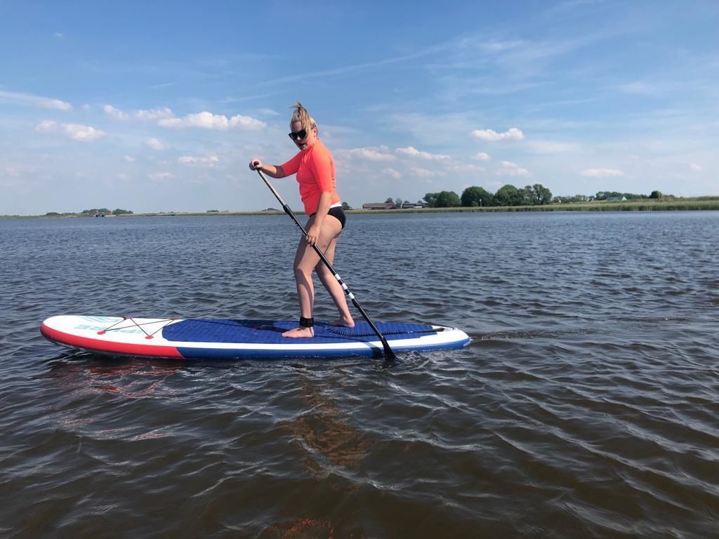 A person paddleboarding on a calm body of water.