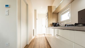 Een moderne keuken met houten vloeren, witte kasten en een raam boven de gootsteen.