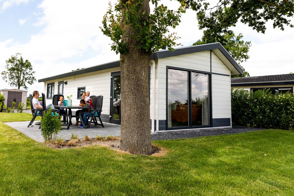 Una casa moderna con un patio donde una familia está sentada.