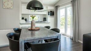 Eine moderne Küche mit Essbereich, ausgestattet mit einem Holztisch, schwarzen Stühlen und einer großen Pendelleuchte.