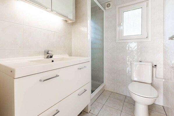 Un baño con lavamanos blanco, inodoro y cabina de ducha.