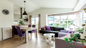 Una sala de estar moderna con comedor, ventanas grandes y vistas al exterior.