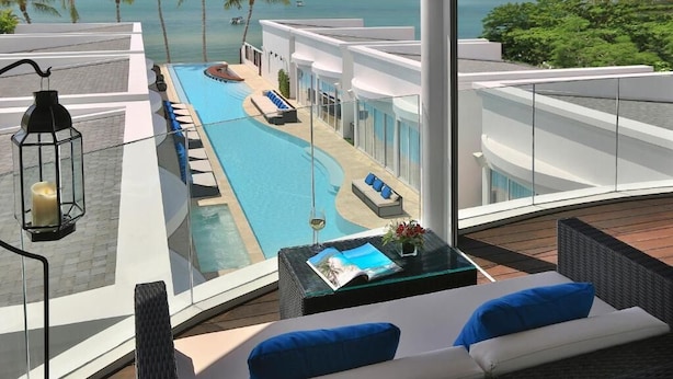A rooftop pool area with a view of the ocean, lounge chairs, and a table with a magazine and flowers. - The Privilege Hotel Ezra Beach Club (Koh Samui)
